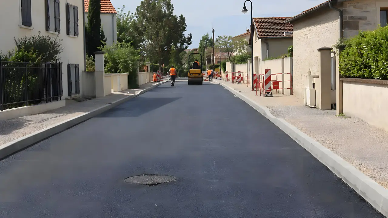 Rue de lotissement à l'enrobé neuf entre des bordures en béton
